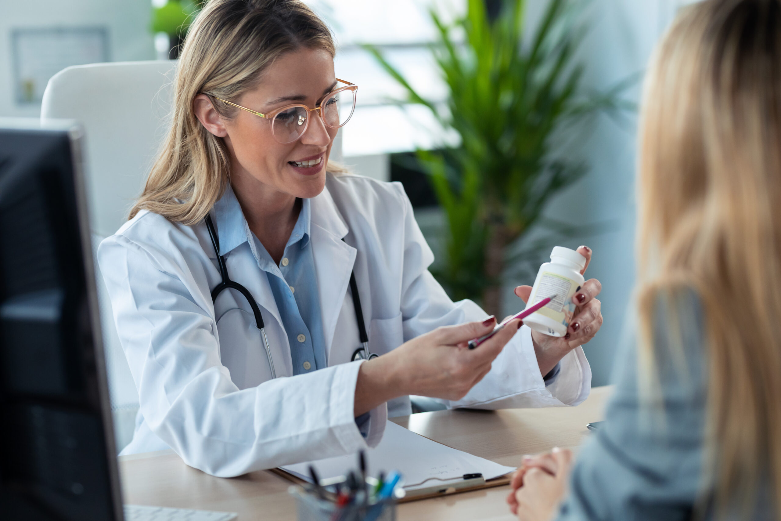 Shot of beautiful mature female doctor talking while explaining medical treatment while prescribing medication to patient in the consultation.