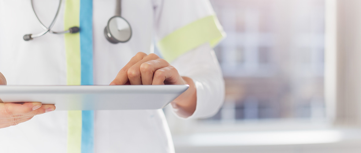 A doctor stands and uses a tablet