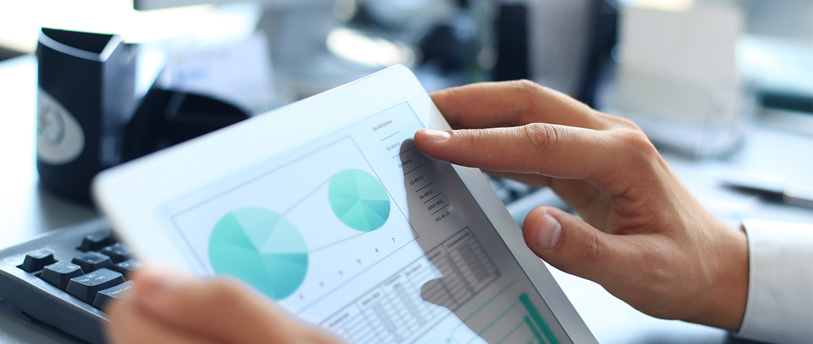 A man uses a tablet with graphs on the screen