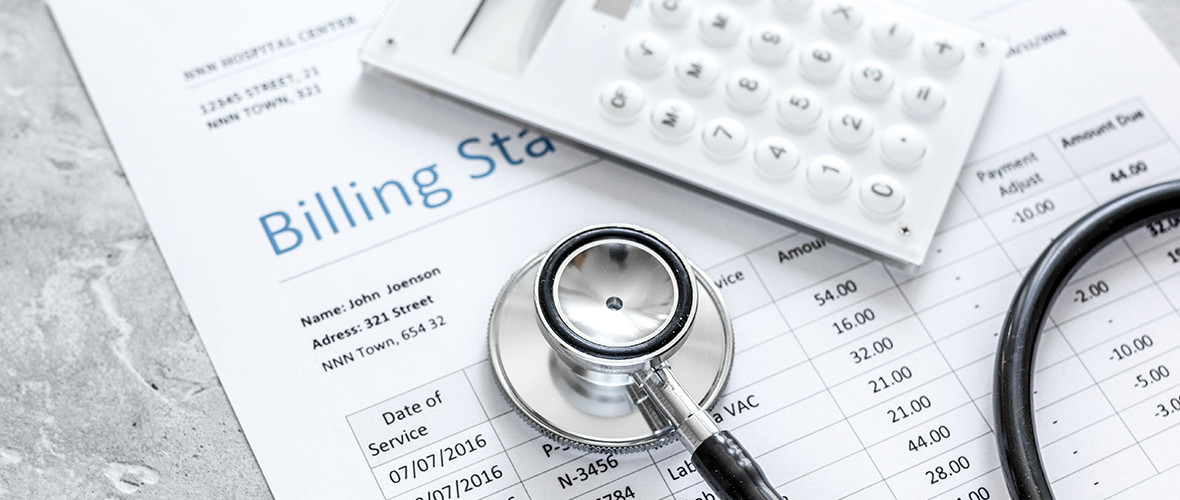A billing statement with a calculator and stethoscope resting on top of it