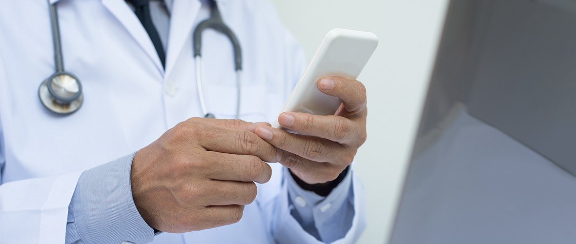 A doctor sits and uses a smartphone