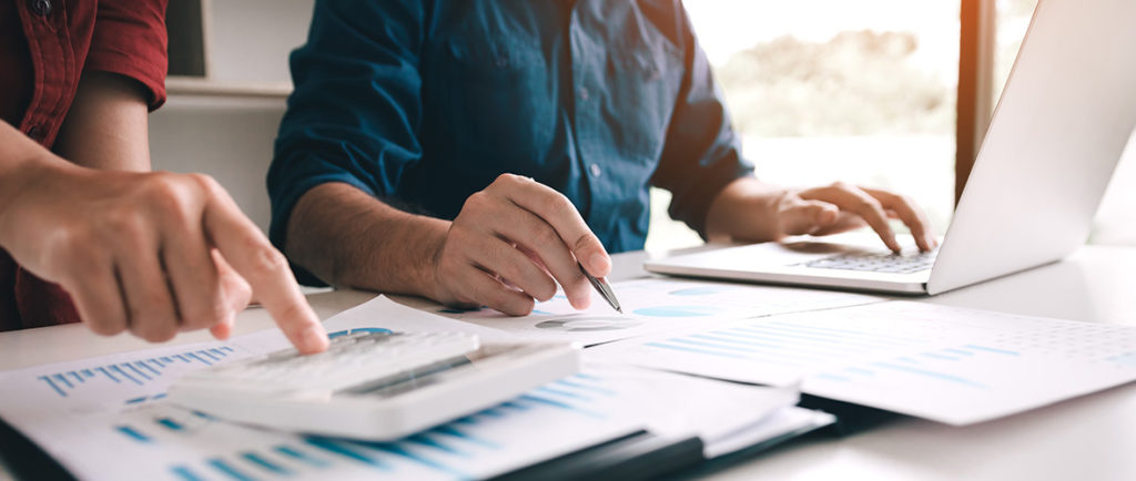 2 men write and point at graphs on a table