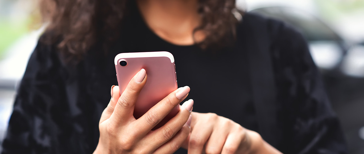 girl standing using a pink smartphone