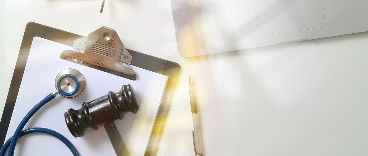 Clipboard and doctor's stethoscope and gavel on a table.