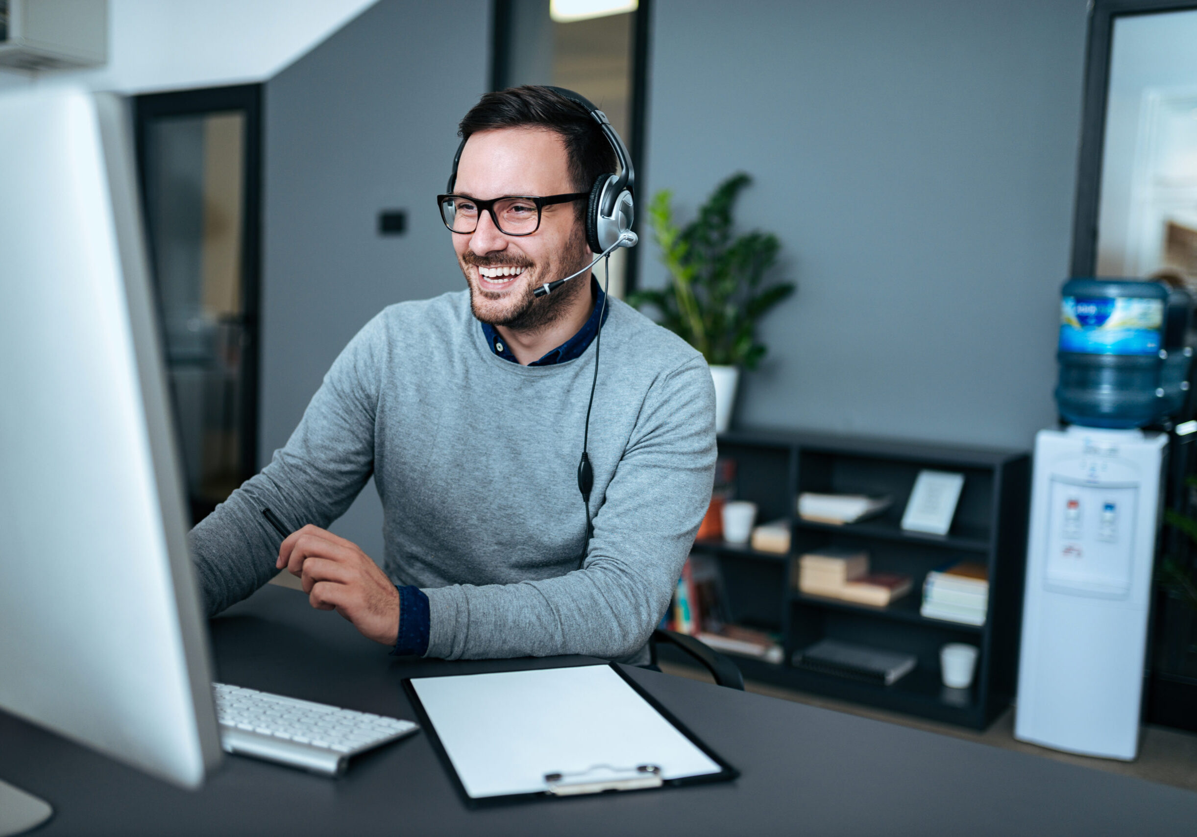 Portrait of a handsome smiling man with headset working on the computer. Customer service & Training