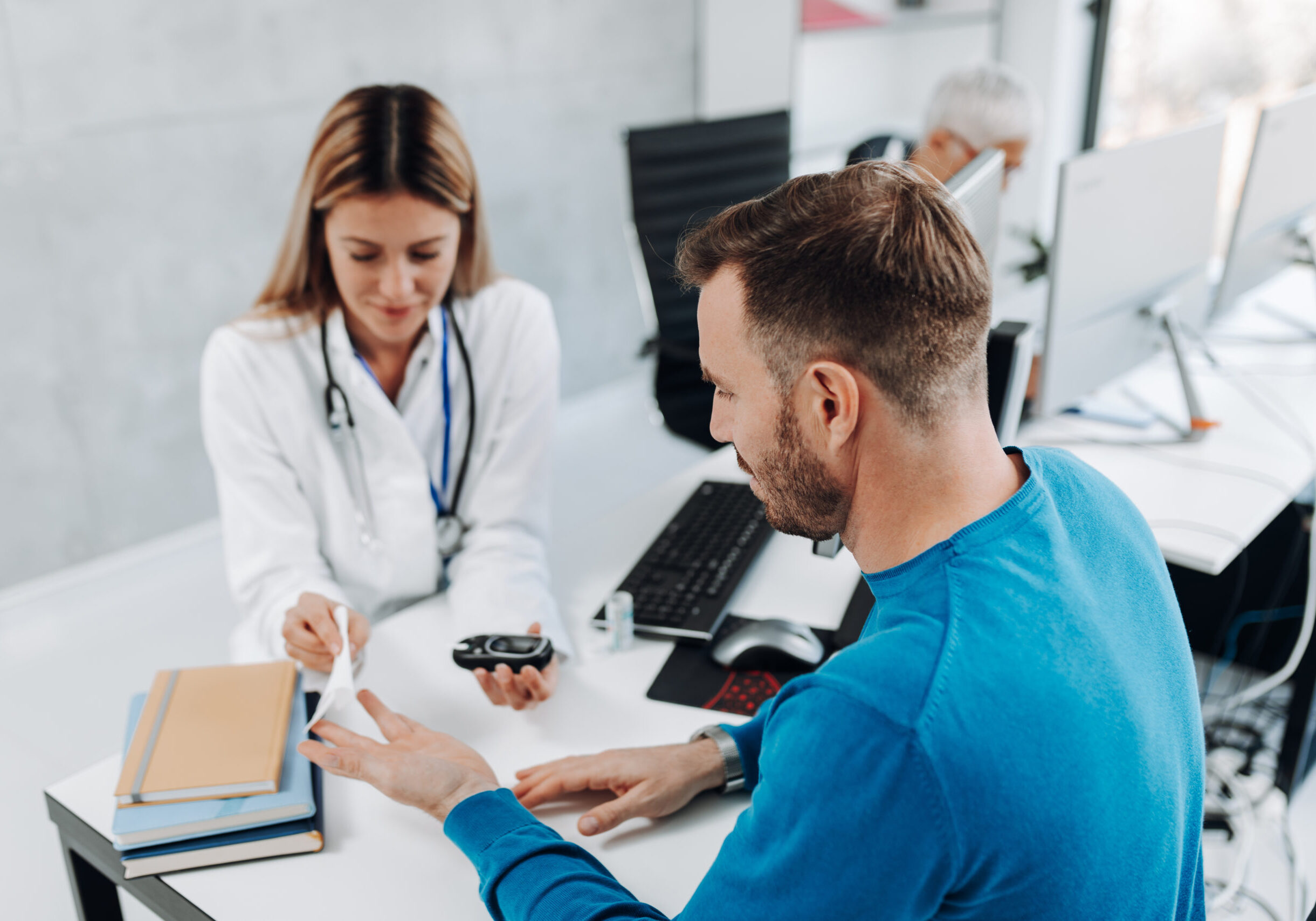 Female doctor measuring the blood sugar level of a young male patient with a glucometer.