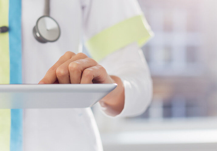 A doctor stands and uses a tablet