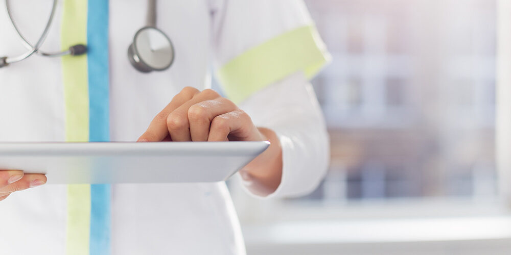 A doctor stands and uses a tablet