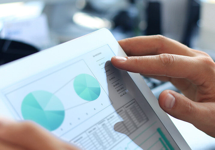 A man uses a tablet with graphs on the screen