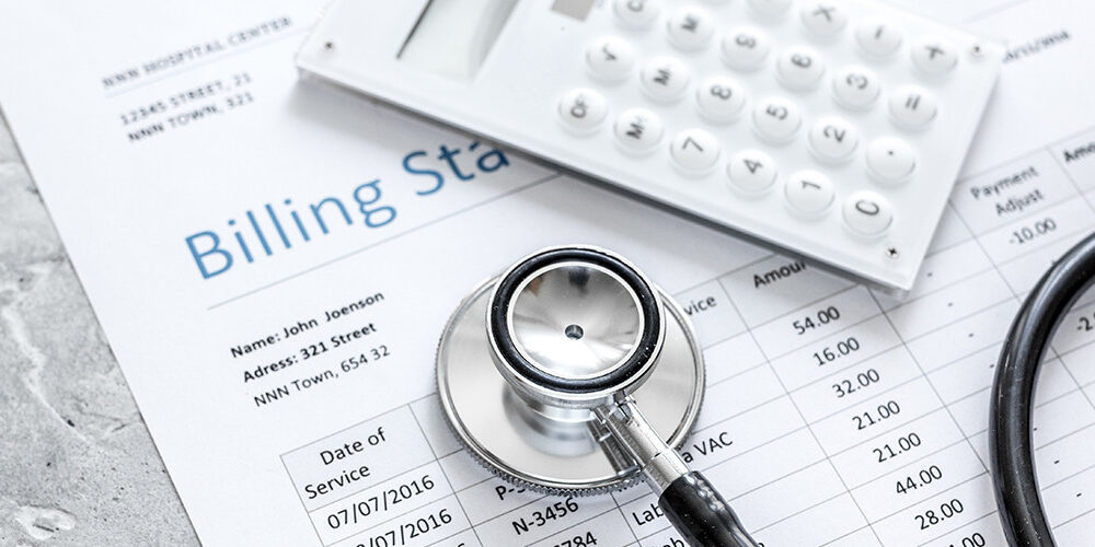 A billing statement with a calculator and stethoscope resting on top of it