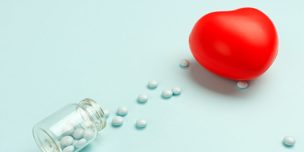 Bottle of white pills spilled out on the table with a heart shaped stress ball