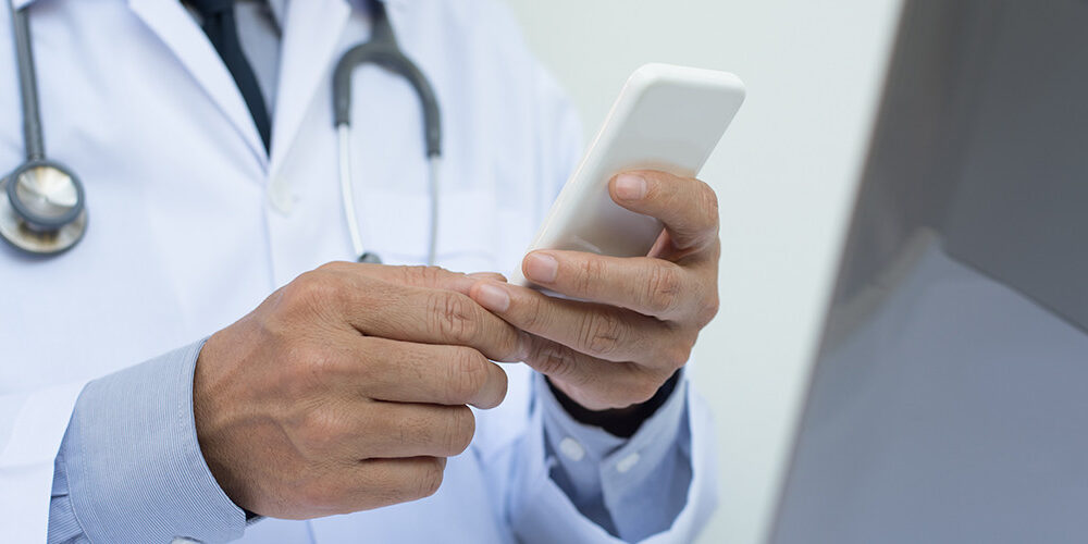 A doctor sits and uses a smartphone