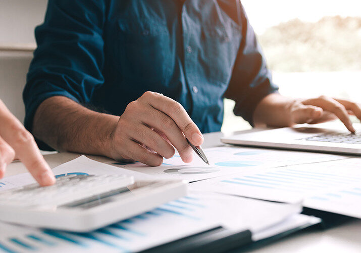 2 men write and point at graphs on a table