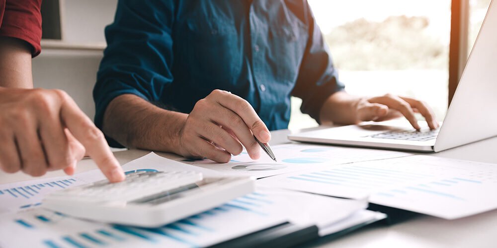 2 men write and point at graphs on a table