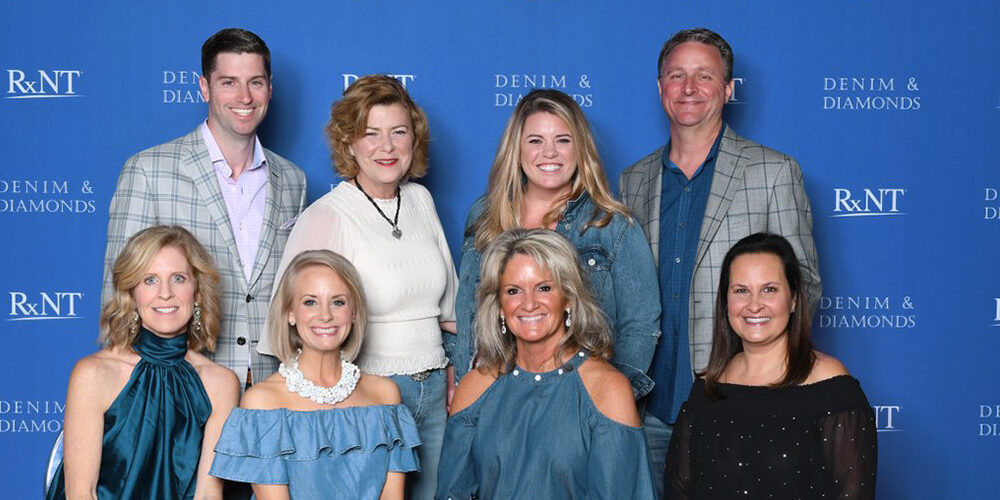 Members of the RXNT team in front of an event banner