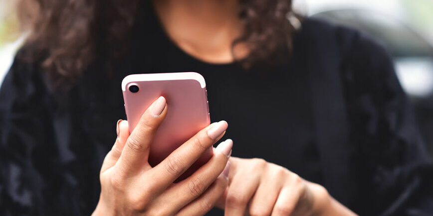 girl standing using a pink smartphone