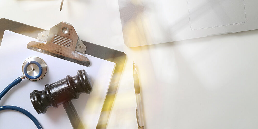 Clipboard and doctor's stethoscope and gavel on a table.